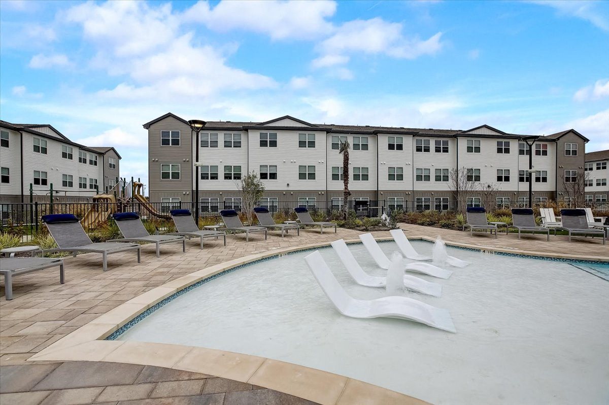 Shallow pool lounge section with in-water chaise seats, perimeter loungers, and open sky views.